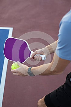 GClose up abstract photo of a man holding a pickleball racket and a pickle ball ready to serveenerated image