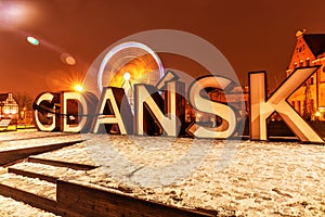 Gdansk city sign and the ferris wheel near Motlawa river, night winter view