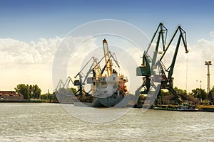 Gdansk, Poland - Jun 21, 2016: many cranes on background, working people, shipping boat.