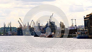 Gdansk, Poland - Jun 21, 2016: many cranes on background, working people, shipping boat.