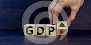 GDP, gross domestic product symbol. Businessman holds a cube with up and down icon. Word `GDP`. Beautiful grey background. Copy