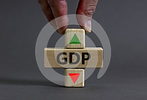 GDP gross domestic product symbol. Businessman holds a cube with up icon. Wooden block with word GDP. Beautiful grey background.