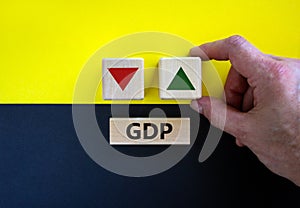 GDP, gross domestic product symbol. Businessman holds a cube with up icon. Wooden block with word `GDP`. Beautiful yellow and