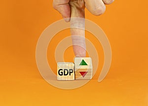 GDP, gross domestic product symbol. Businessman turns a cube with up and down icon. Word `GDP`. Beautiful orange background. Cop