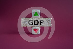 GDP symbol. A wooden cubes with up arrow. Brick block with the concept word GDP . Beautiful red background. Business and GDP