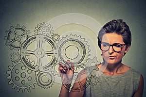 Gears and ideas creativity concept. Woman in glasses drawing gears with pen