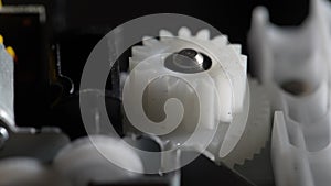 Gears rotating in mechanical device. Machine white plastic gears rotating