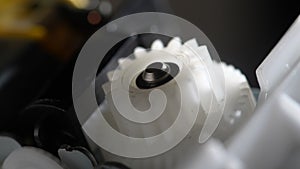 Gears rotating in mechanical device. Machine white plastic gears rotating