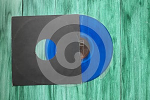 Ged black paper cover and blue vinyl LP record isolated on green background