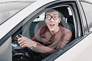 geek driver is staring at the camera and holding the steering wheel. Concept of a novice driver and learning to drive