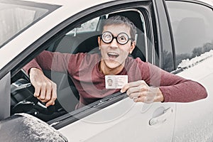 Geek in huge ridiculous glasses shows his driver`s license. Concept of vision correction and fools on the road