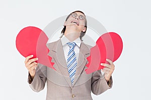 Geeky businessman crying and holding broken heart card