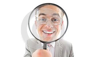 Geeky businessman looking through magnifying glass