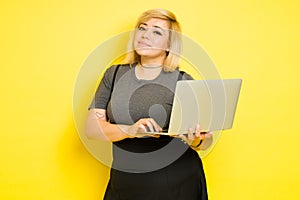 Geeky fat woman holding a laptop computer and looking confident in a studio