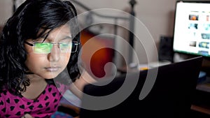 Geeky girl indian asian caucasian working on laptop wearing glasses spectacles at home office. Close up on eye glasses reflection