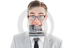 Geeky smiling businessman biting calculator