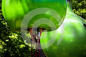 Geen play pods hanging in playground in front of trees with little girls legs and feet sticking out the bottom