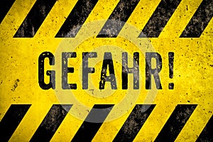 GEFAHR! in German, danger warning sign text with yellow and black stripes painted over concrete wall cement texture background