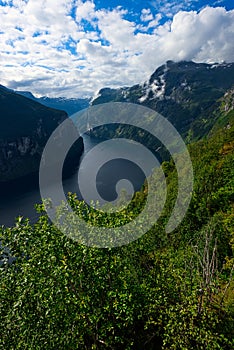 Geiranger Fjord, Norway on a sunny day with a cloudy blue sky