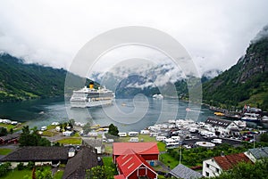 Geiranger, Norway - January 25, 2010: ship in norwegian fjord on cloudy sky. Ocean liner in village harbor. Travel destination, to