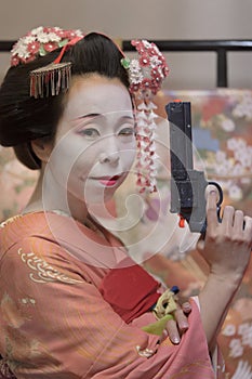 Geisha girl in kimono holding a plastic gun in her hand.