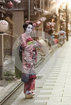 Geisha walking in an alley of Kyoto in the sunset light.