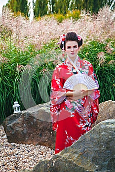 Geisha woman with a fan in garden