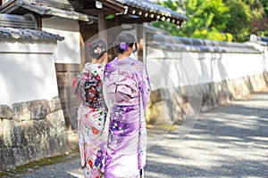 Geishas girl wearing Japanese kimono among red wooden Tori Gate at Fushimi Inari Shrine in Kyoto, Kimono is a Japanese traditional