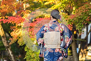 Geishas girl wearing Japanese kimono among red wooden Tori Gate at Fushimi Inari Shrine in Kyoto, Kimono is a Japanese traditional