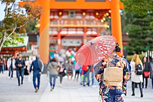 Geishas girl wearing Japanese kimono among red wooden Tori Gate at Fushimi Inari Shrine in Kyoto, Kimono is a Japanese traditional