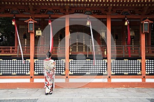 Geishas girl wearing Japanese kimono among red wooden Tori Gate at Fushimi Inari Shrine in Kyoto