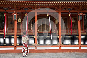 Geishas girl wearing Japanese kimono among red wooden Tori Gate at Fushimi Inari Shrine in Kyoto