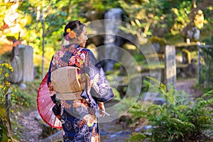 Geishas girl wearing Japanese kimono among red wooden Tori Gate at Fushimi Inari Shrine in Kyoto, Kimono is a Japanese traditional