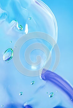 Gel texture of cosmetic products. transparent cream on a blue background with bubbles. macro photo. blur and selective