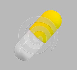 A gelatin capsule with yellow cap on grey background closeup