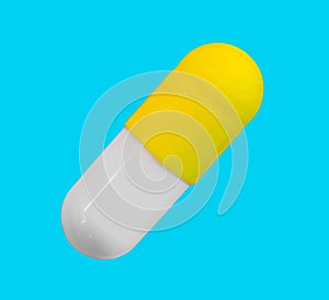 A gelatin capsule with yellow cap isolated on a blue background closeup