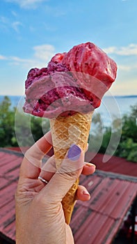 Gelato ice cream cone held up to the hot summer city