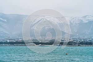 Gelendzhik city in winter in snowy weather, mountains covered with snow, waves and wind on sea bay water surface, no