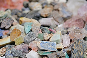 Gem stones. Unpolished gem stones scattered on the ground. selective focus on the black stone