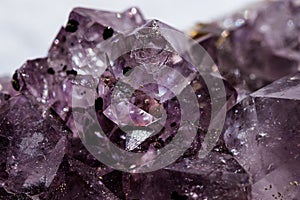 Gemstone Amethyst closeup as a part of cluster geode filled with rock Quartz crystals.