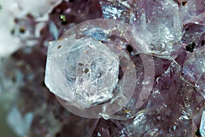 Gemstone Amethyst closeup as a part of cluster geode filled with rock Quartz crystals.