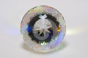 Gemstone of clear Optical K9 glass with Round Brilliant Portuguese cut, on a white Plexiglas background, photographed straight fro