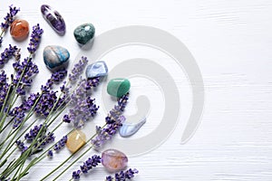 Gemstones and healing herbs on white table, flat lay. Space for text