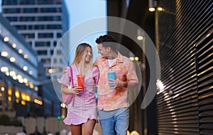 Gen Z couple in pink outfits leaving the cinema with drinks in hand.