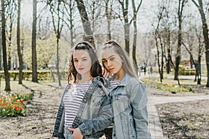 Gen z girls enjoying outdoors, expressing positive emotions. Outdoor photo of two girl friends having fun in the park
