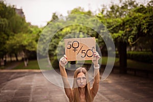 Gender equality concept as woman hands holding a paper sheet with male and female symbol over a crowded city street