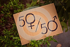 Gender equality concept: paper sheet with male and female symbol over a crowded city street background. Sex sign as a metaphor of