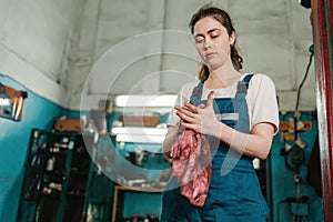 Gender equality. Portrait of a strong young woman in uniform, working in a workshop, which wipes his hands with a rag. Bottom view