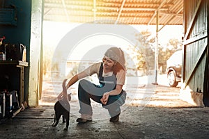 Gender equality. Portrait of a young smiling brunette woman in a work uniform who is squatting and stroking a black cat. Street in