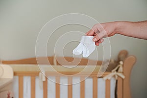 Gender-neutral names. Unisex nursery gender neutral. Calm nursery color palette games. Hands hold baby socks on the background of